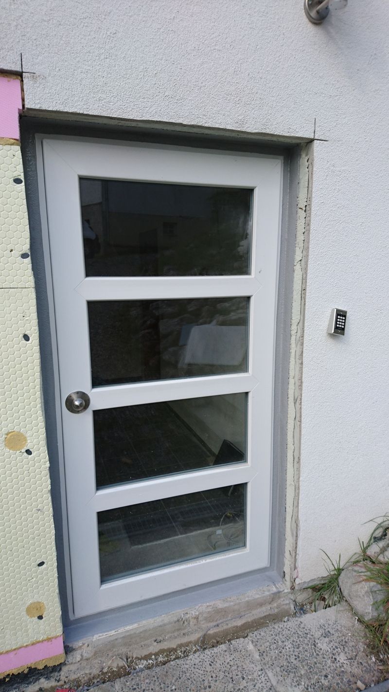 Tür mit drei rechteckigen Fenstereinsätzen in einer weißen Wand